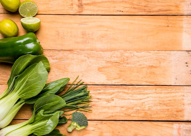 Lemons; bell peppers; broccoli; chives and bokchoy on wooden plank