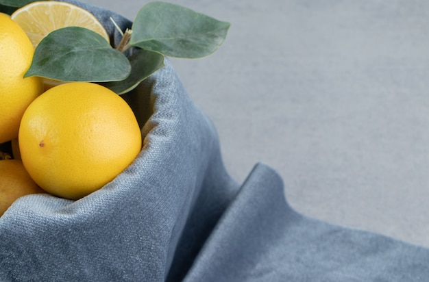 Lemons in a bucket covered with a fabric piece on marble 