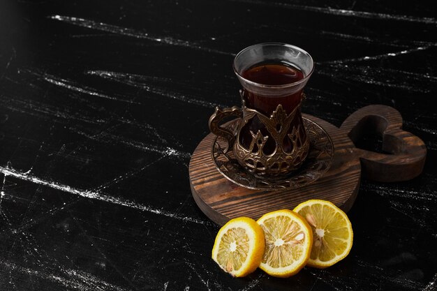 Lemons isolated on a black background with a glass of tea.