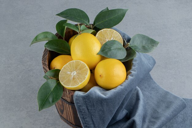 Лимоны и листья сложены в ведро на мраморе