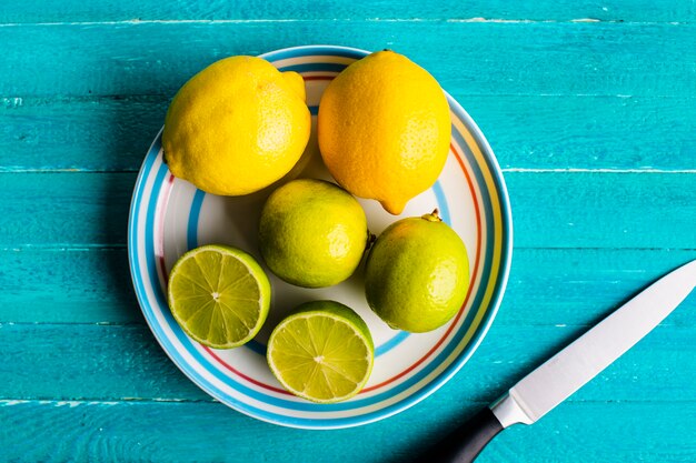 Лимоны и лайм на тарелке на столе