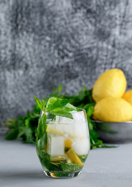 Лимон и мята в миске с ледяным детокс-водным взглядом на гранж и серой поверхности