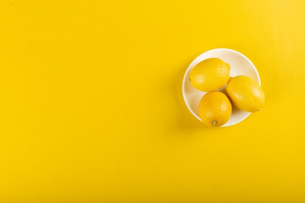 Lemons in a white saucer on yellow