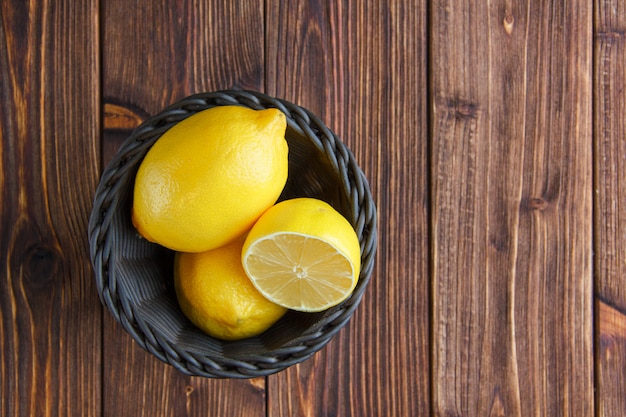 Лимоны в плетеной корзине на деревянном столе. плоская планировка