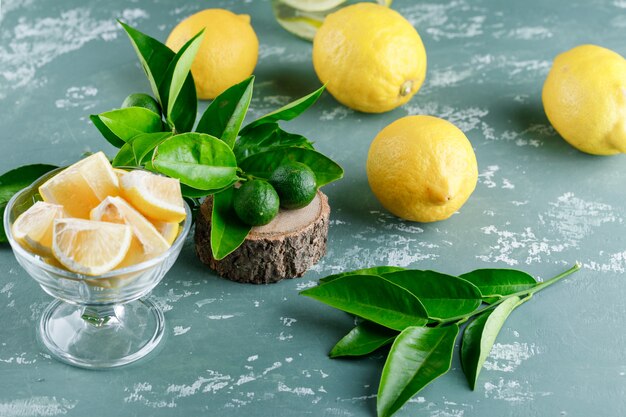 Lemons with leaves, wooden board high angle view on a plaster surface