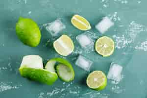 Free photo lemons with peel, ice cubes flat lay on a plaster