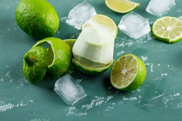 Free photo lemons with peel, ice cubes on plaster, high angle view.