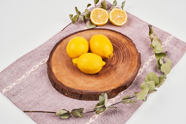 Free photo lemons on wooden platter with leaves.