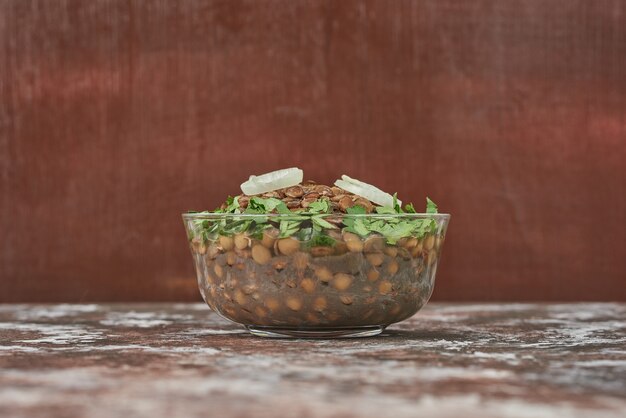 Lentil salad in a glass cup with herbs .