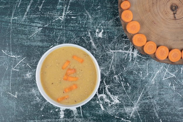 Бесплатное фото Чечевичный суп в белой миске и ломтики моркови. фото высокого качества