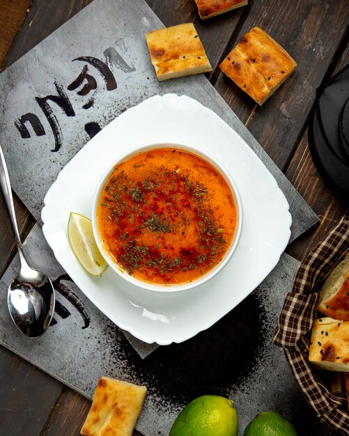 Lentil soup sprinkled with spices and a slice of lemon top view