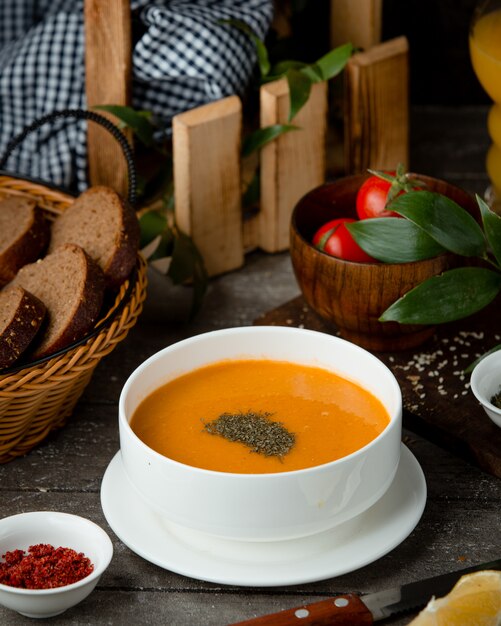 lentil soup in a white bowl and a basket of bread