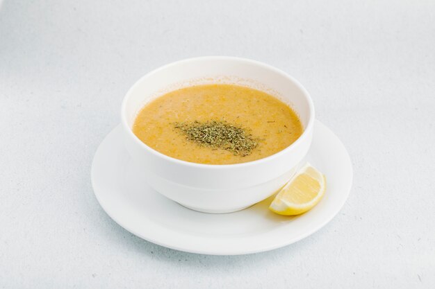 Lentil soup with herbs and spices in white bowl.