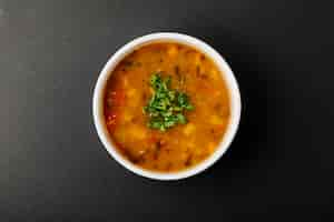 Free photo lentil soup with mixed ingredients and herbs in a white bowl.