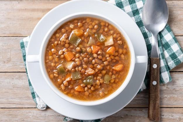 Lentil soup with vegetables in bowl on wooden table