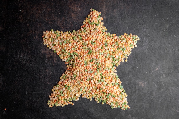 Free photo lentils forming star shape on a dark textured background. top view.