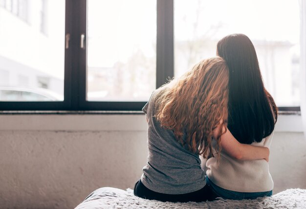 Lesbian couple embracing near window