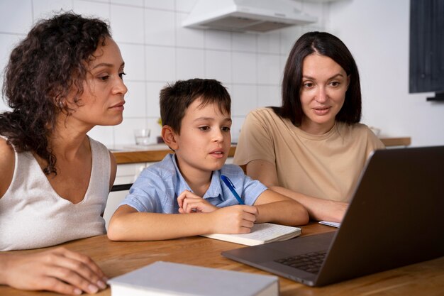 Lesbian couple helping their son to do his homework