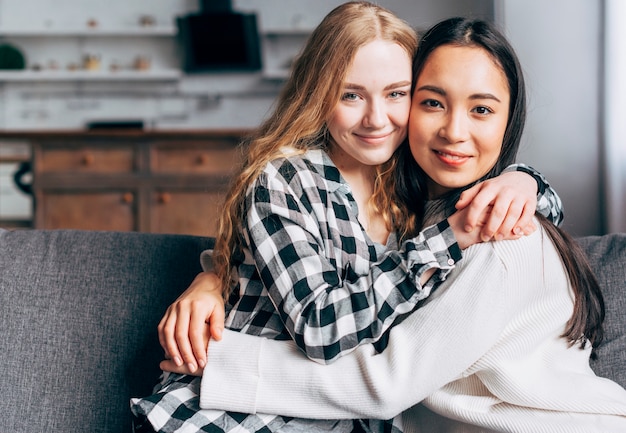 Lesbian couple hugging and looking at camera 