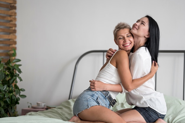 Free photo lesbian couple hugging while sitting in bed