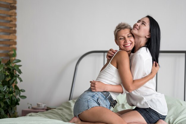 Lesbian couple hugging while sitting in bed