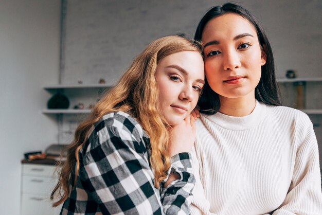 Lesbian couple looking at camera at home