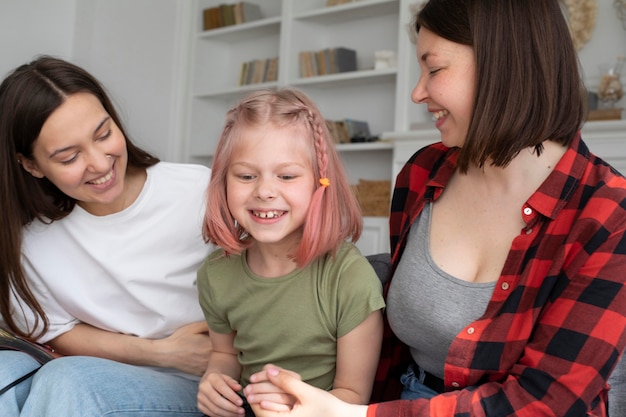 Free photo lesbian couple spending time with their daughter at home