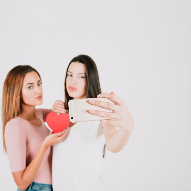 Lesbian couple taking selfie with heart