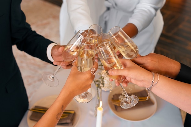 Free photo lesbian couple toasting champagne with guests at their wedding