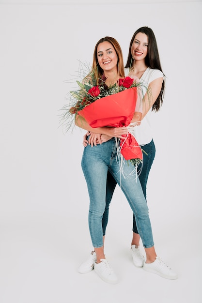 Lesbian women with bunch of flowers embracing