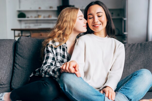 Lesbians sitting on sofa and enjoying each other