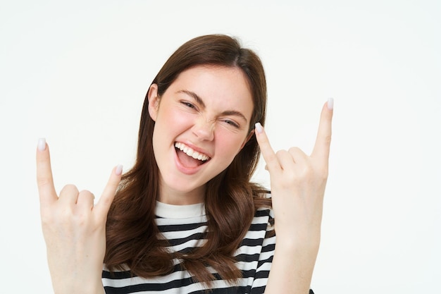 Let it rock excited laughing young woman showing heavy metal horns gesture and smiling having fun