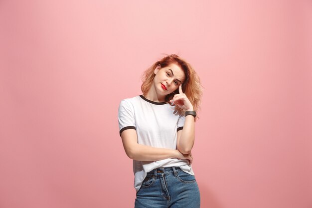 Let me think. Doubtful pensive woman with thoughtful expression making choice against pink wall