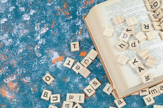 Letter dominoes made from wood and isolated on the blue pattern surface