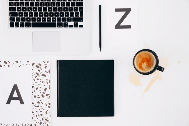 문자 a와 z; 연필; 일기; 흰색 배경에서 노트북과 엎지른 된 커피 컵