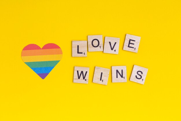 Lgbt heart icon and word love wins on wooden blocks