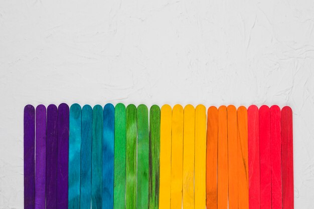 ЛГБТ радуга разноцветных деревянных палочек на серой поверхности