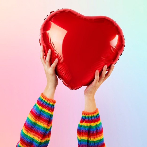 Free photo lgbtq+ community heart balloon held by hands