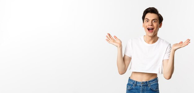 Lgbtq and pride concept handsome young man in crop top raising hands up and looking surprised rejoic