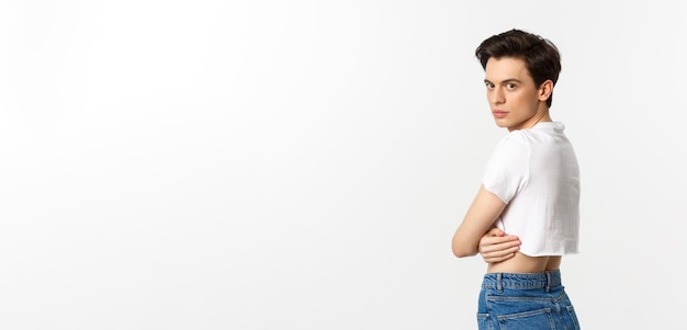 Lgbtq and pride concept profile view of beautiful gay man in crop top turn head at camera staring wi