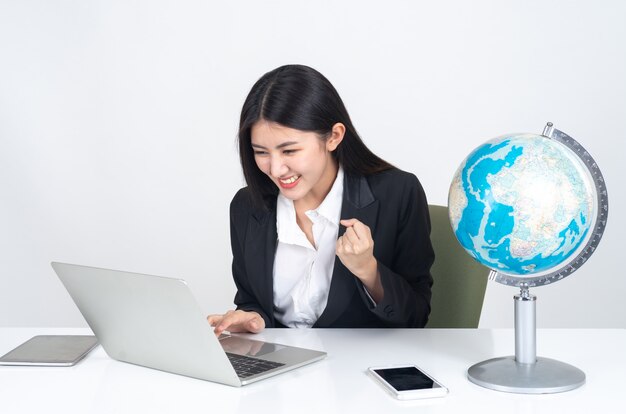 ライフスタイル美しいアジアビジネス若い女性のオフィスの机の上にラップトップコンピューターとスマートフォンを使用して