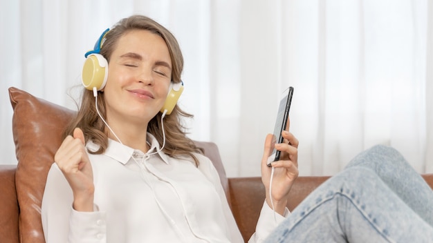 Lifestyle Beautiful cute girl woman feel happy enjoy listening to music with earphones headphones on sofa