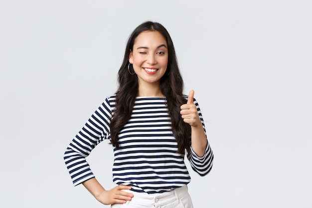 Lifestyle, beauty and fashion, people emotions concept. Cheerful cute asian girl thumb-up in approval, wink encouraging and smiling, praising nice job, say well played as congratulate with win