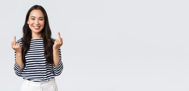 Free photo lifestyle beauty and fashion people emotions concept unbothered and careless young happy smiling woman dont give a damn showing middle fingers and feeling good white background