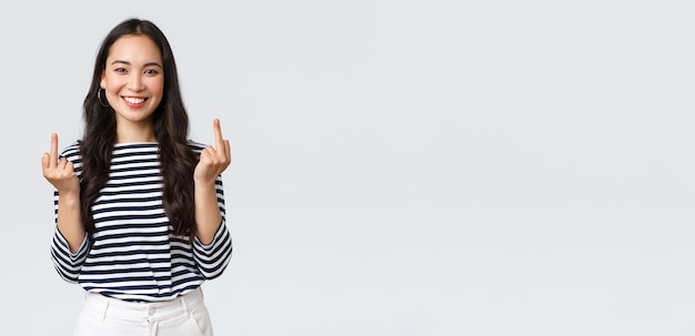 Lifestyle beauty and fashion people emotions concept Unbothered and careless young happy smiling woman dont give a damn showing middle fingers and feeling good white background