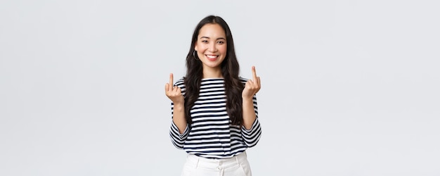 Free photo lifestyle beauty and fashion people emotions concept unbothered and careless young happy smiling woman dont give a damn showing middle fingers and feeling good white background
