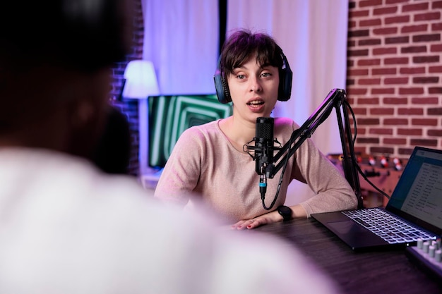 Free photo lifestyle blogger having conversation with female guest, recording podcast with sound equipment. influencer talking to cheerful woman to broadcast live discussion to record in studio.