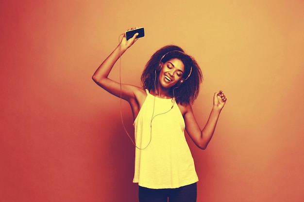 휴대 전화 복사 공간에서 음악을 즐겁게 듣고 있는 아름다운 아프리카계 미국인 여성의 라이프스타일 개념 초상화