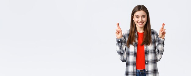 Lifestyle different emotions leisure activities concept Hopeful cute caucasian girl in checked shirt making wish cross fingers good luck and smiling optimistic white background