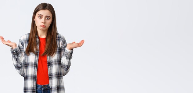 Lifestyle different emotions leisure activities concept Reluctant and careless young woman shrugging with hands spread sideways dont know cant help have no idea stand white background